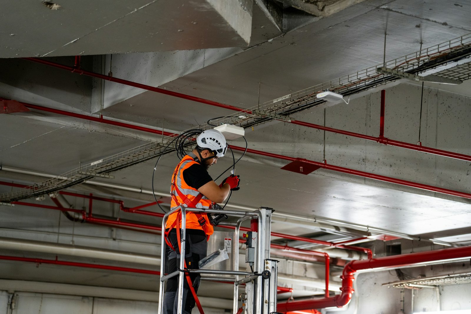 Engineer installing fire fighting sprinkler pipework at ceiling level